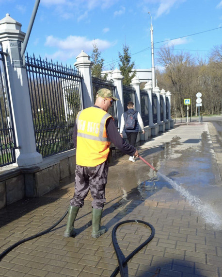 Коммунальщики моют тротуары в городе специальными средствами.